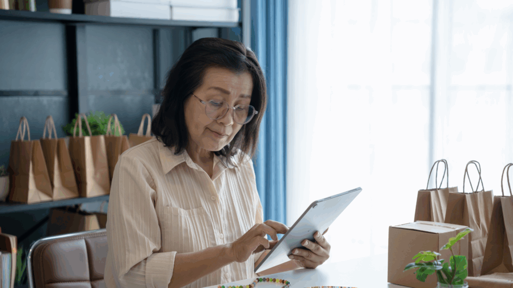 An older Asian business owner looking at orders on her tablet.