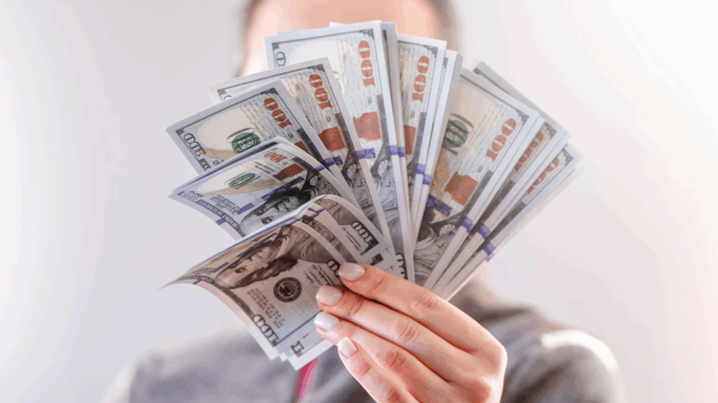 A person holding up several 100 dollar bills